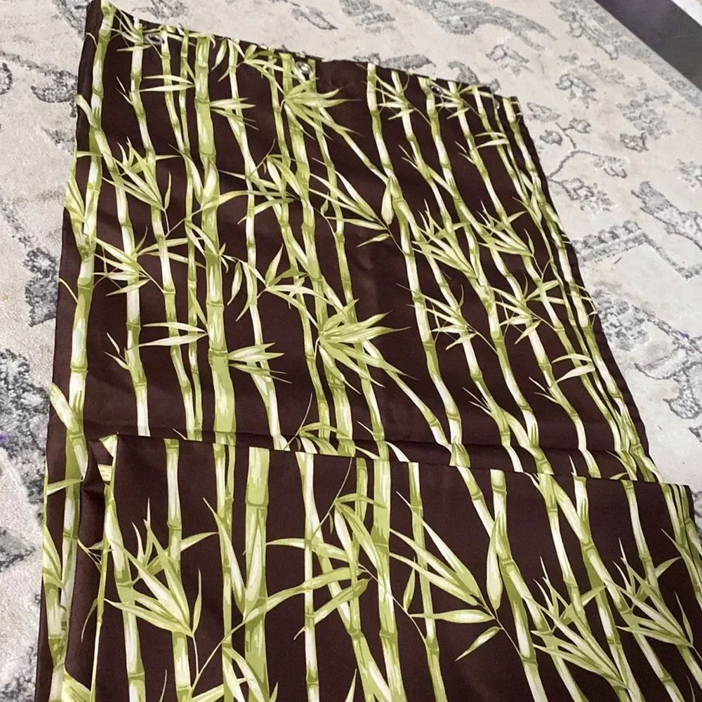 Brown shower curtain with bamboo in green has metal grommets to hang in shower
